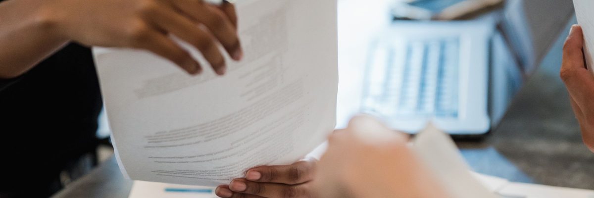 Hands exchanging documents across a meeting table